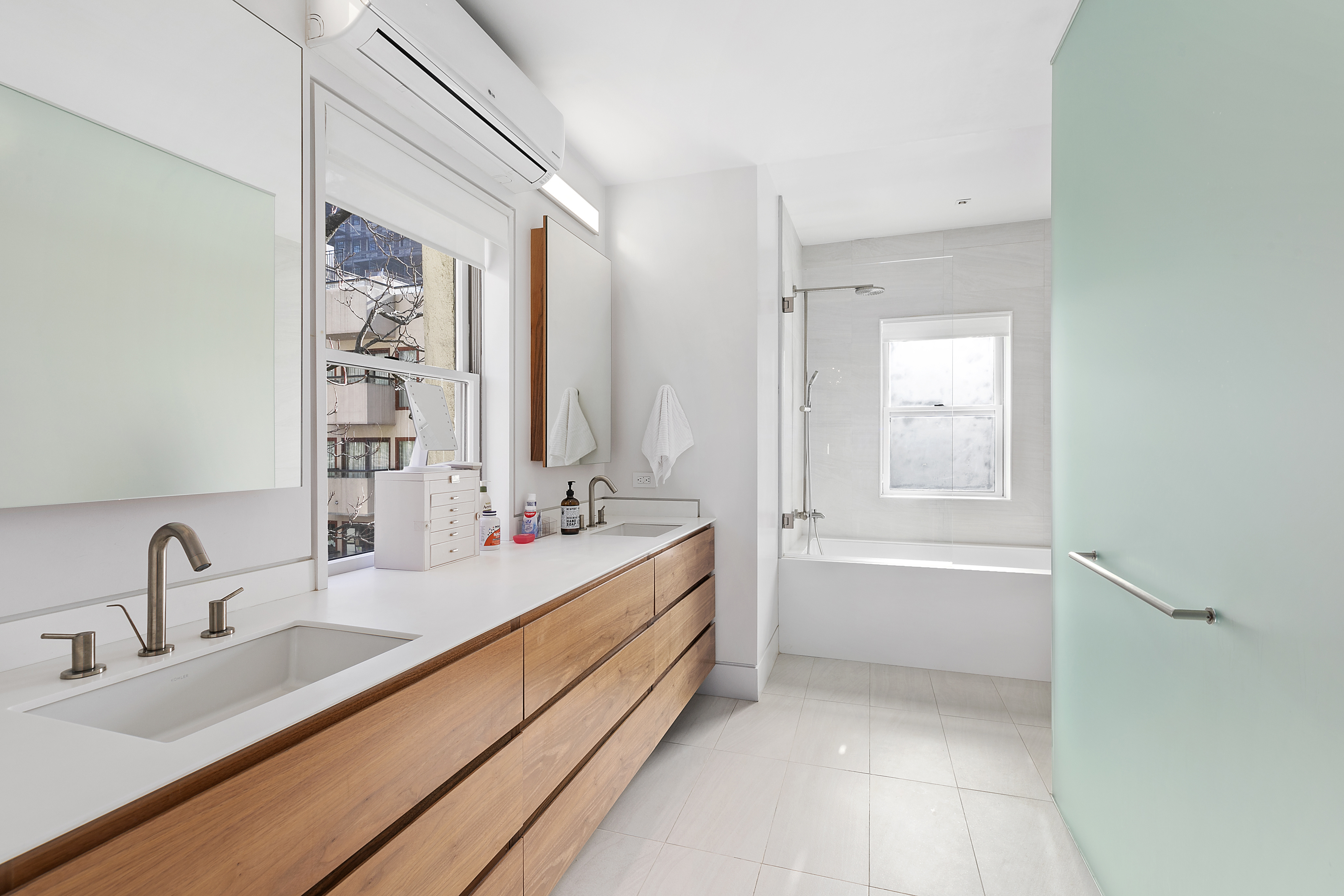 36 East 64th Street Manhattan, NY 10065 - Photo 22 of 27 a bathroom with a double vanity sink tub and mirror