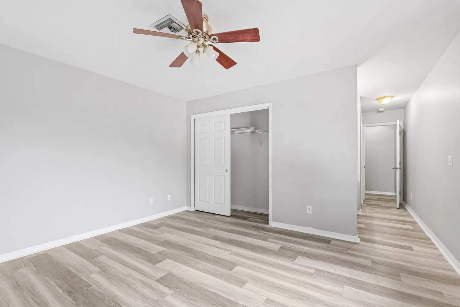 a view of a room with wooden floor and ceiling fan