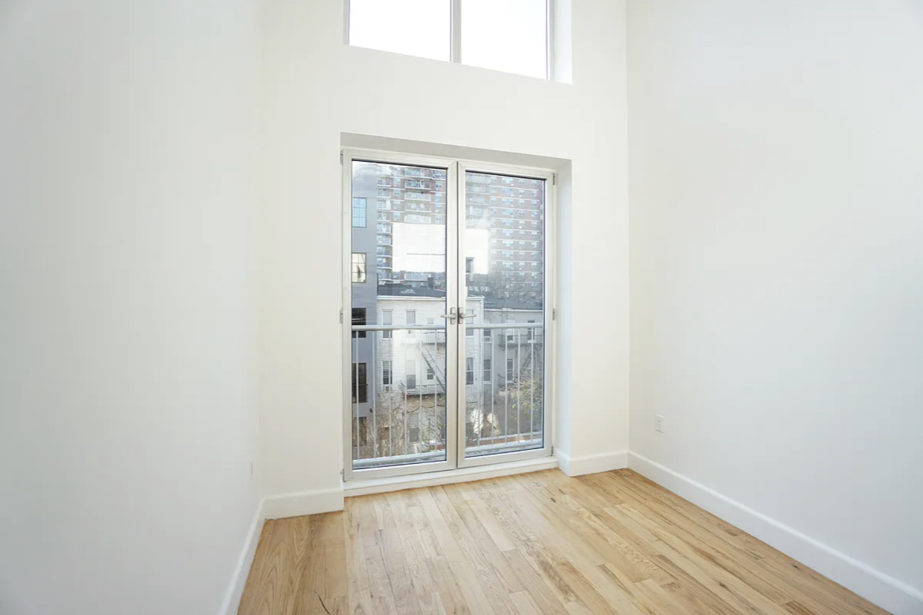 42-44 Meserole Street, Unit 2 Brooklyn, NY 11206 - Photo 6 of 8 a view of an empty room with wooden floor and a window