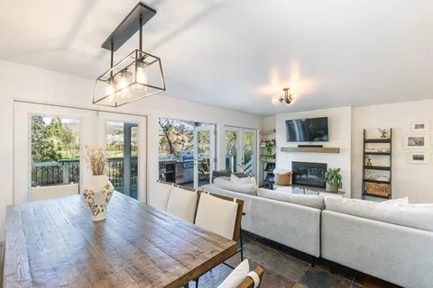 a living room with furniture a fireplace and a dining table with wooden floor