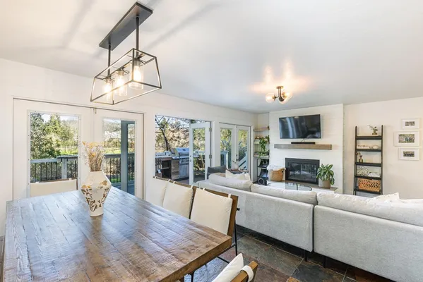 a living room with furniture a fireplace and a dining table with wooden floor