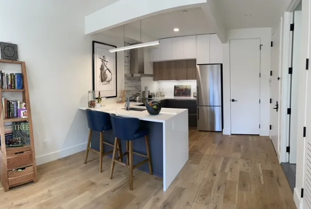 a kitchen with stainless steel appliances a dining table chairs refrigerator and sink