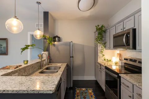 a kitchen with stainless steel appliances granite countertop a sink a stove and a refrigerator