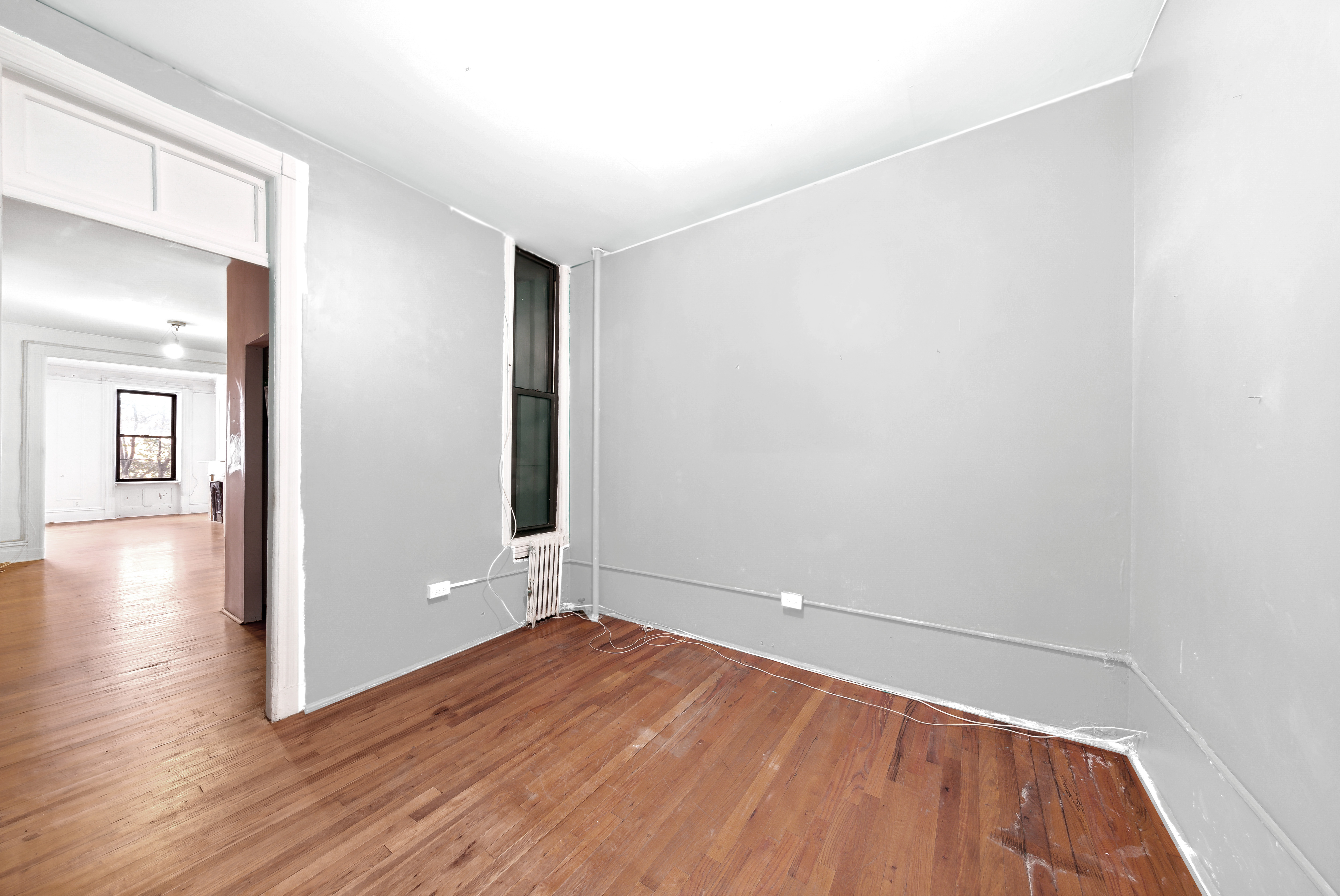 206 East 90th Street, Unit 2E Manhattan, NY 10128 - Photo 6 of 13 an empty room with wooden floor and windows