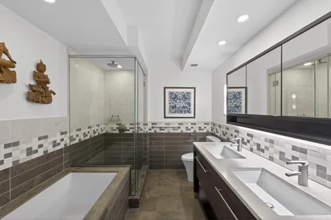 a bathroom with a bathtub a double vanity sink and mirror
