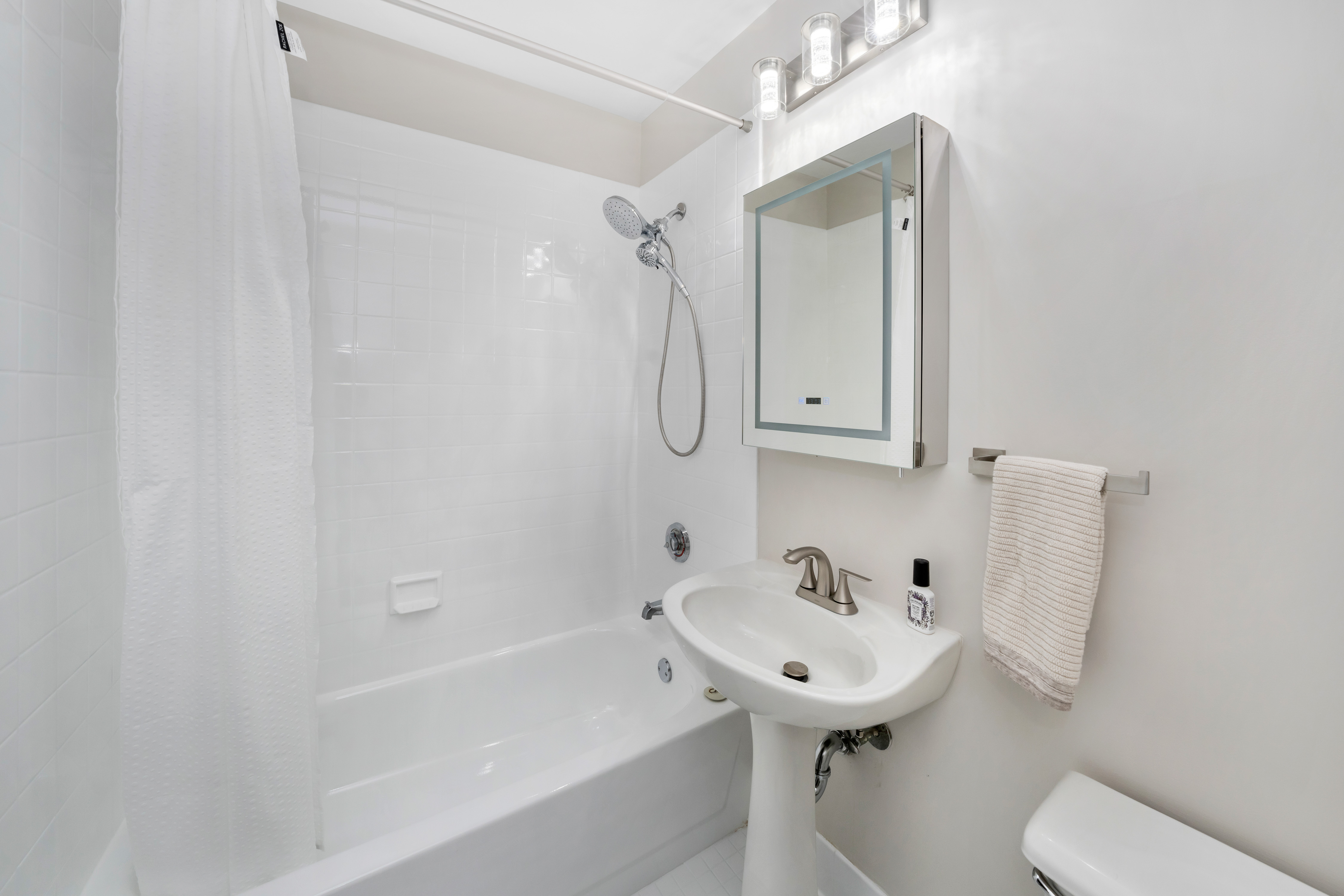 4-74 48th Avenue, Unit 19B Queens, NY 11109 - Photo 9 of 10 a bathroom with a sink a toilet and bathtub