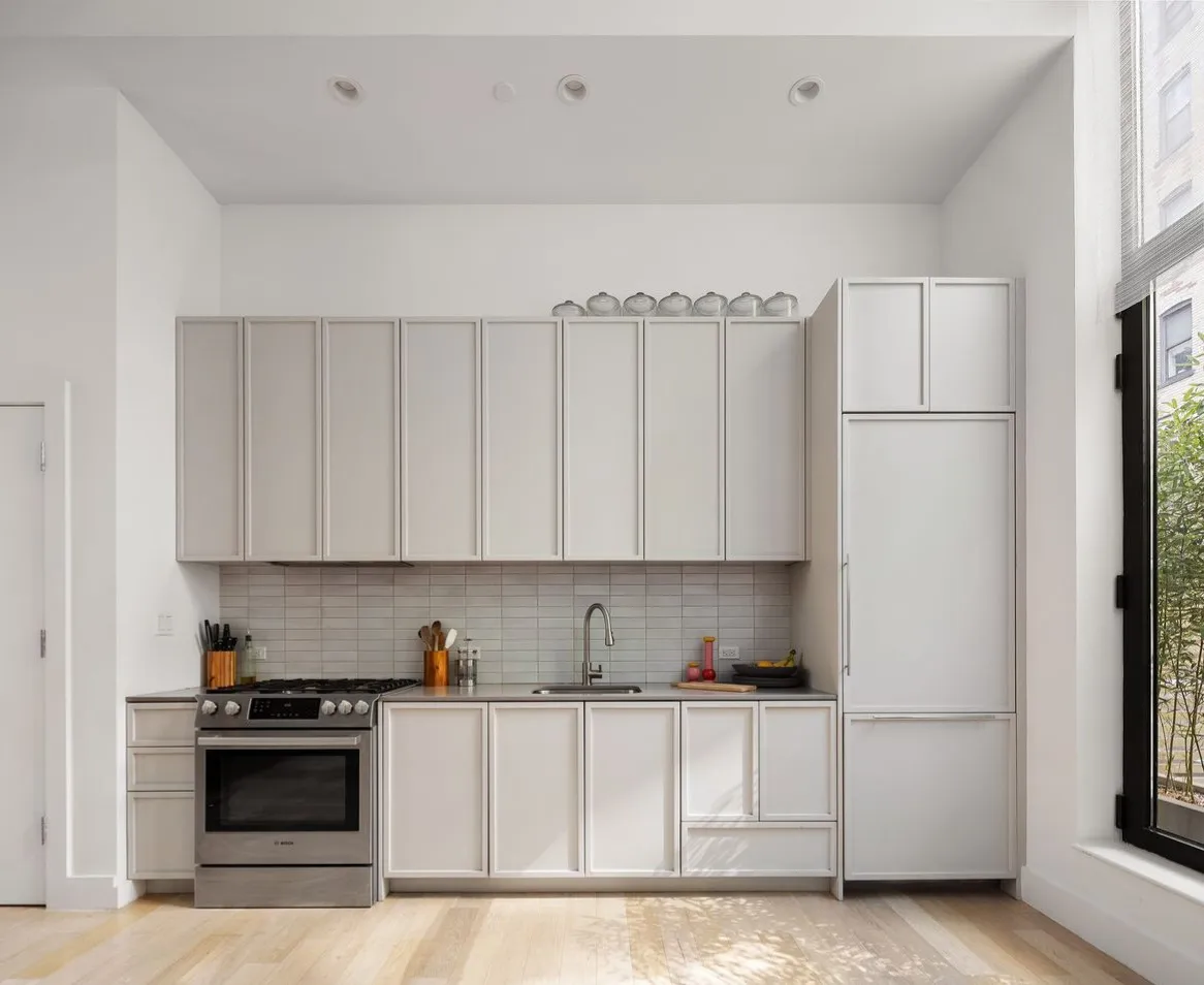 a kitchen with stainless steel appliances granite countertop a refrigerator sink stove and white cabinets