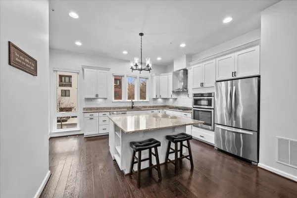 a kitchen with kitchen island white cabinets and stainless steel appliances