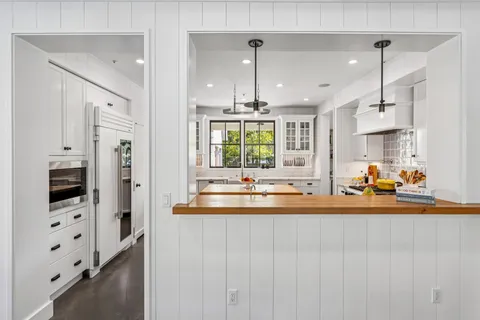 a large kitchen with stainless steel appliances a large counter top a stove a chimney and a refrigerator