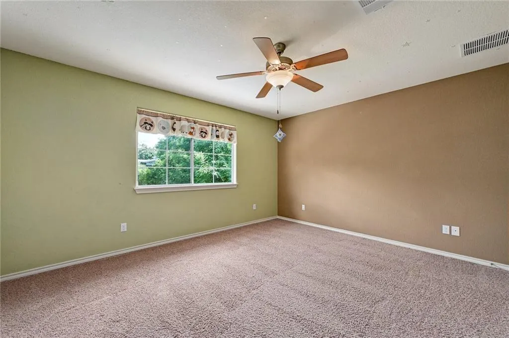 an empty room with a window and a fan