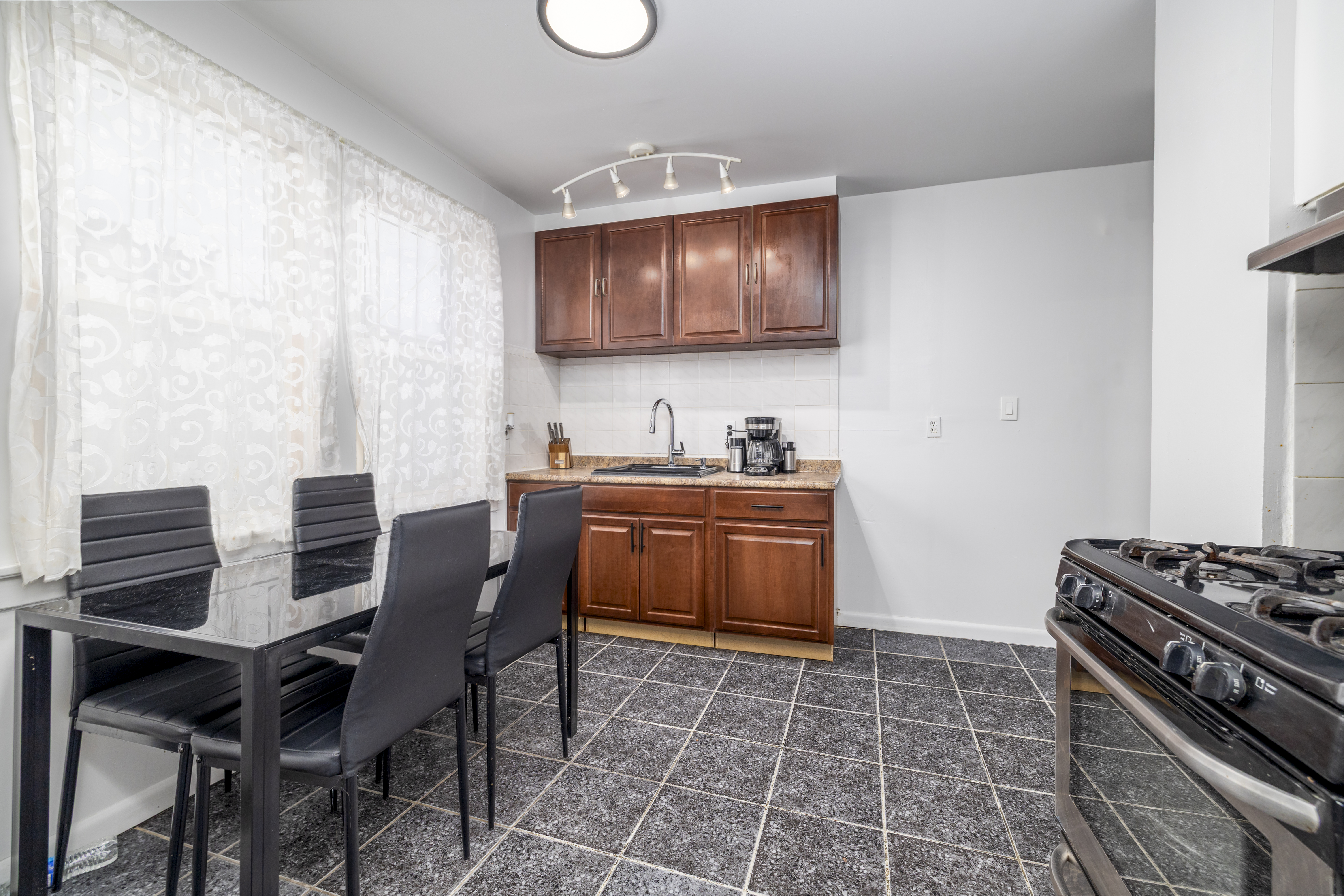 87-46 89th Street Queens, NY 11421 - Photo 7 of 25 a kitchen with a table chairs and a stove