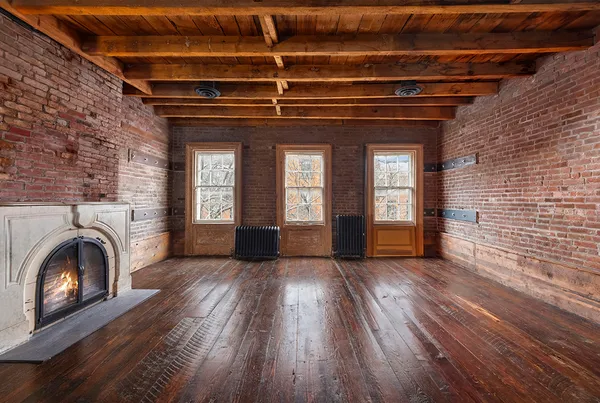 a view of an empty room with wooden floor fireplace and a window