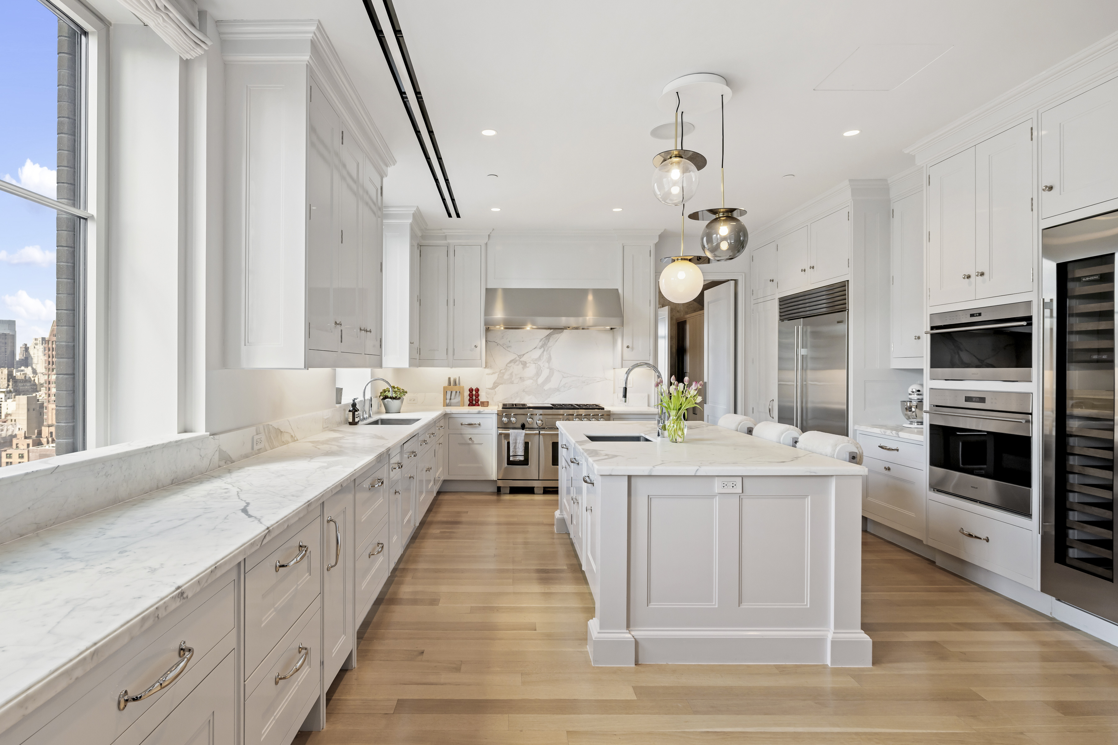 301 East 80th Street, Unit 25B Manhattan, NY 10075 - Photo 10 of 38 a large kitchen with stainless steel appliances kitchen island granite countertop a sink dishwasher a dining table and chairs with wooden floor