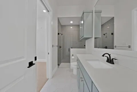 a bathroom with a sink a toilet a mirror and shower