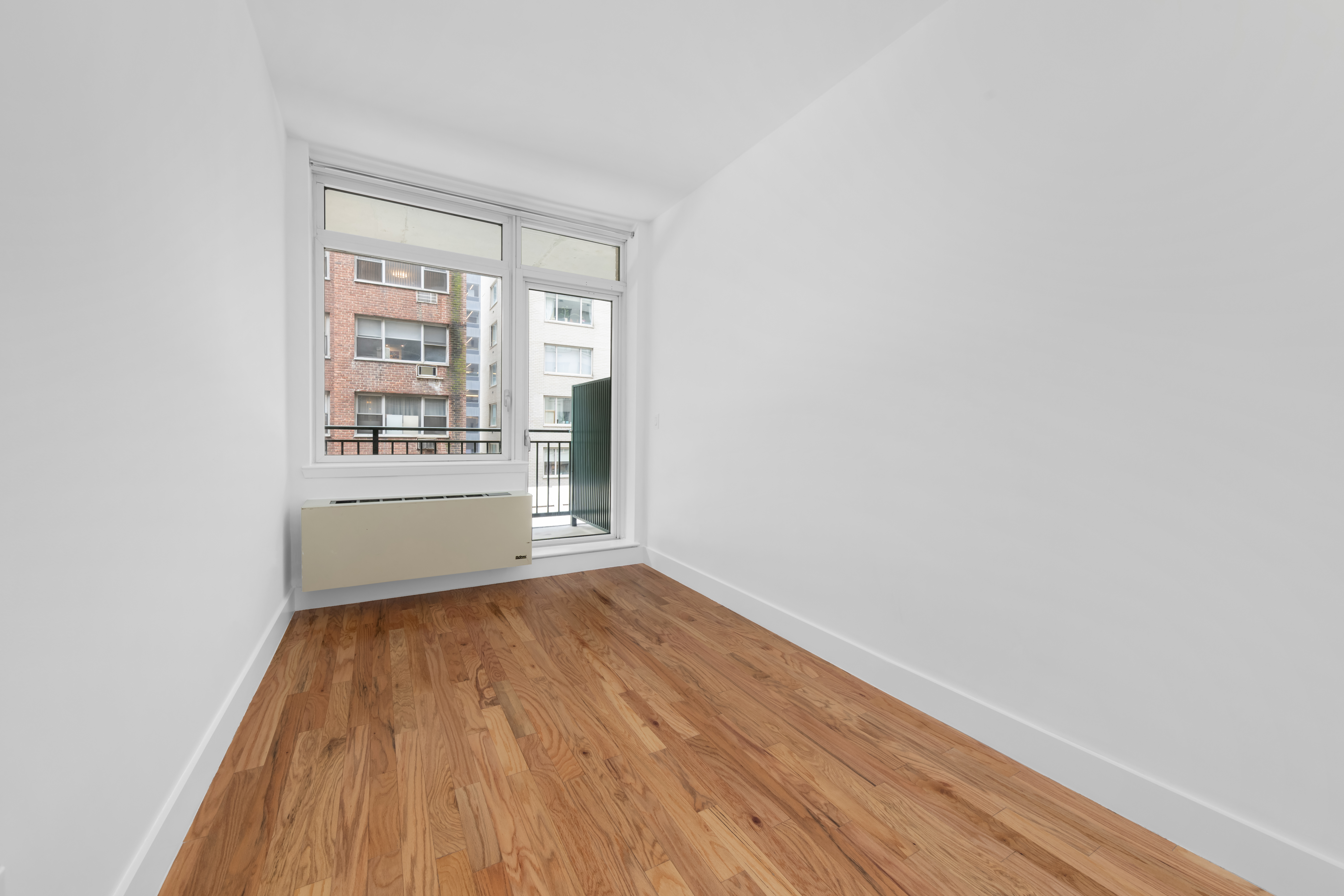 212 East 57th Street, Unit 3B Manhattan, NY 10022 - Photo 5 of 17 a view of an empty room with a window and wooden floor