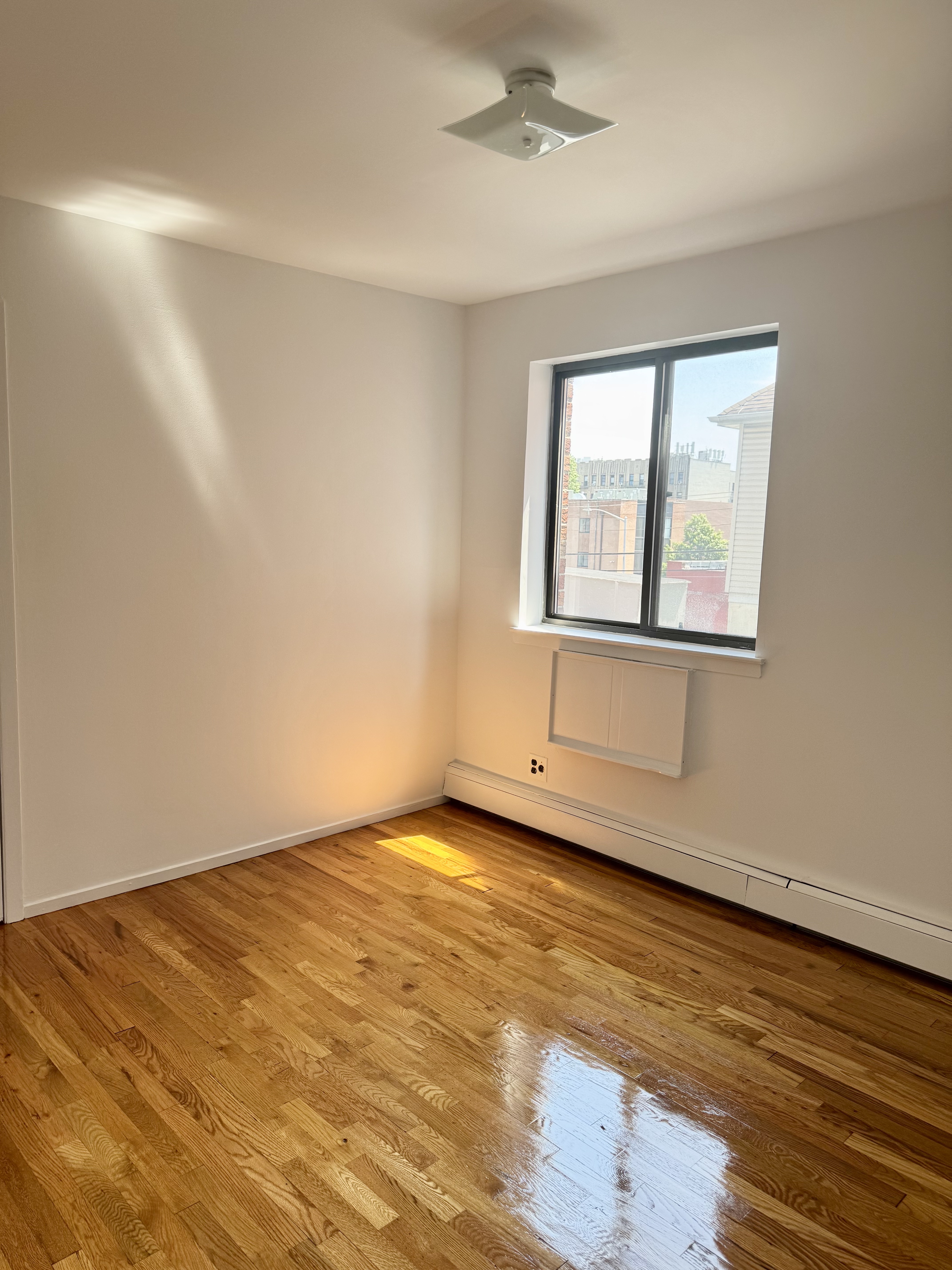 59-15 39th Avenue, Unit 2 Queens, NY 11377 - Photo 4 of 13 a view of an empty room with wooden floor and a window