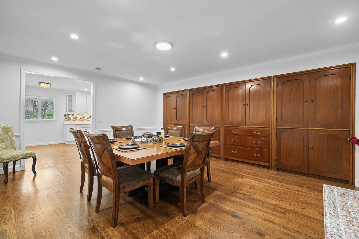 a dining room with wooden floor a chandelier a glass table and chairs