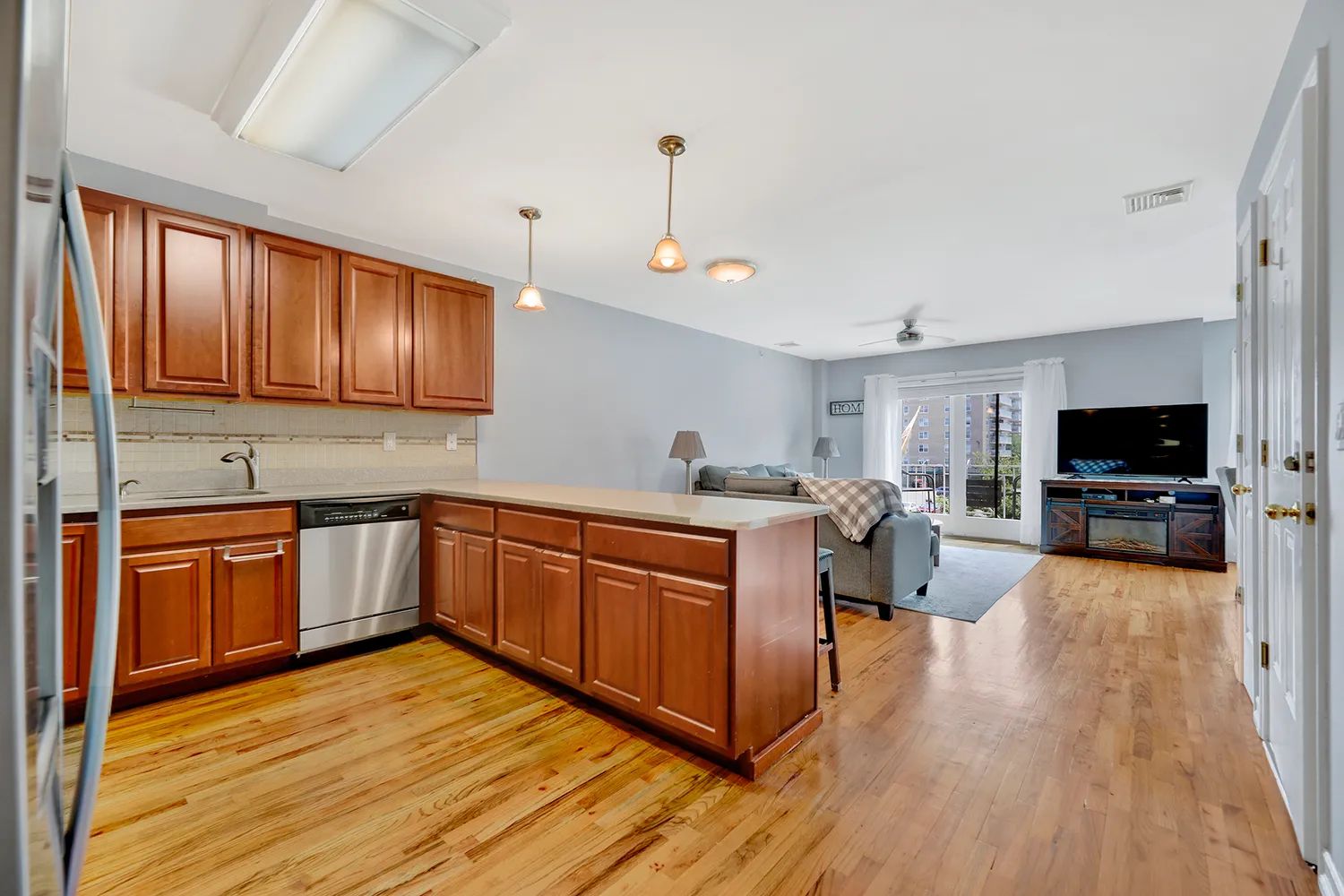 a kitchen with stainless steel appliances granite countertop wooden cabinets a sink dishwasher a stove and a refrigerator with wooden floor