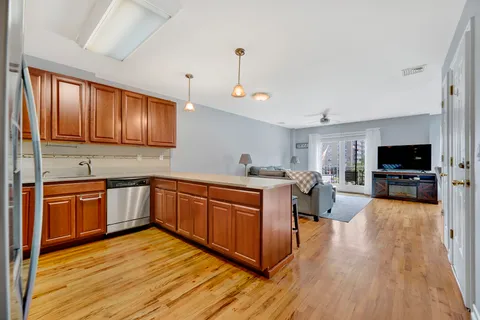 a kitchen with stainless steel appliances granite countertop wooden cabinets a sink dishwasher a stove and a refrigerator with wooden floor