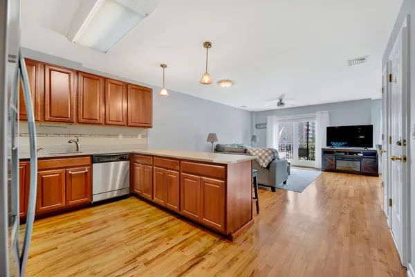 a kitchen with stainless steel appliances granite countertop wooden cabinets a sink dishwasher a stove and a refrigerator with wooden floor