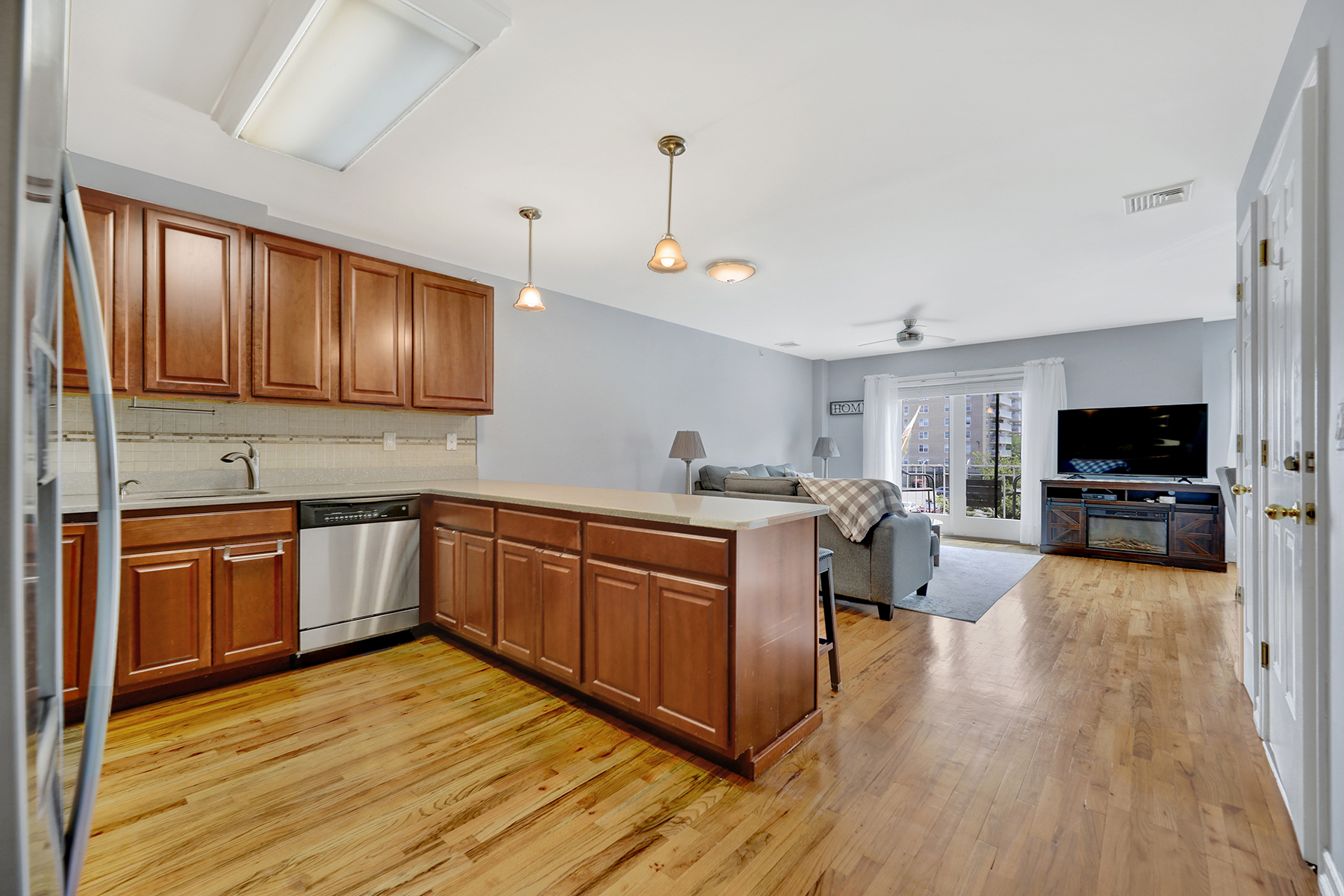 102-20 Rockaway Beach Boulevard, Unit 3C Queens, NY 11694 - Photo 4 of 36 a kitchen with stainless steel appliances granite countertop wooden cabinets a sink dishwasher a stove and a refrigerator with wooden floor