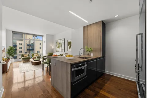 a view of a kitchen with kitchen island a stove a refrigerator and a view of living room