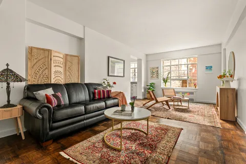 a living room with furniture a rug a window and a table