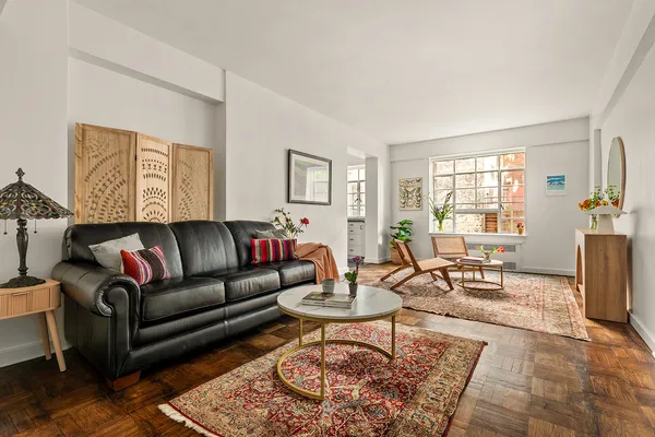 a living room with furniture a rug a window and a table
