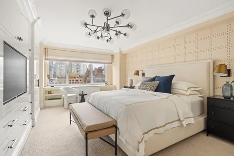 a bedroom with a large bed and a flat tv screen on dresser