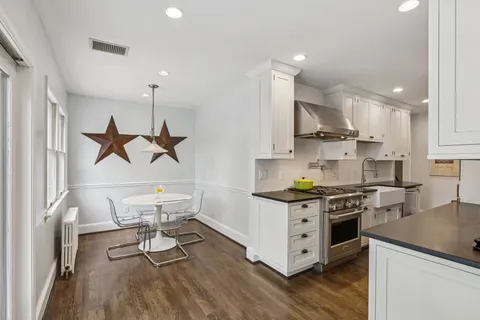a kitchen with a stove a sink and wooden floor