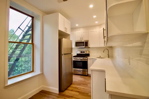 a kitchen with a refrigerator a stove top oven a sink and a window