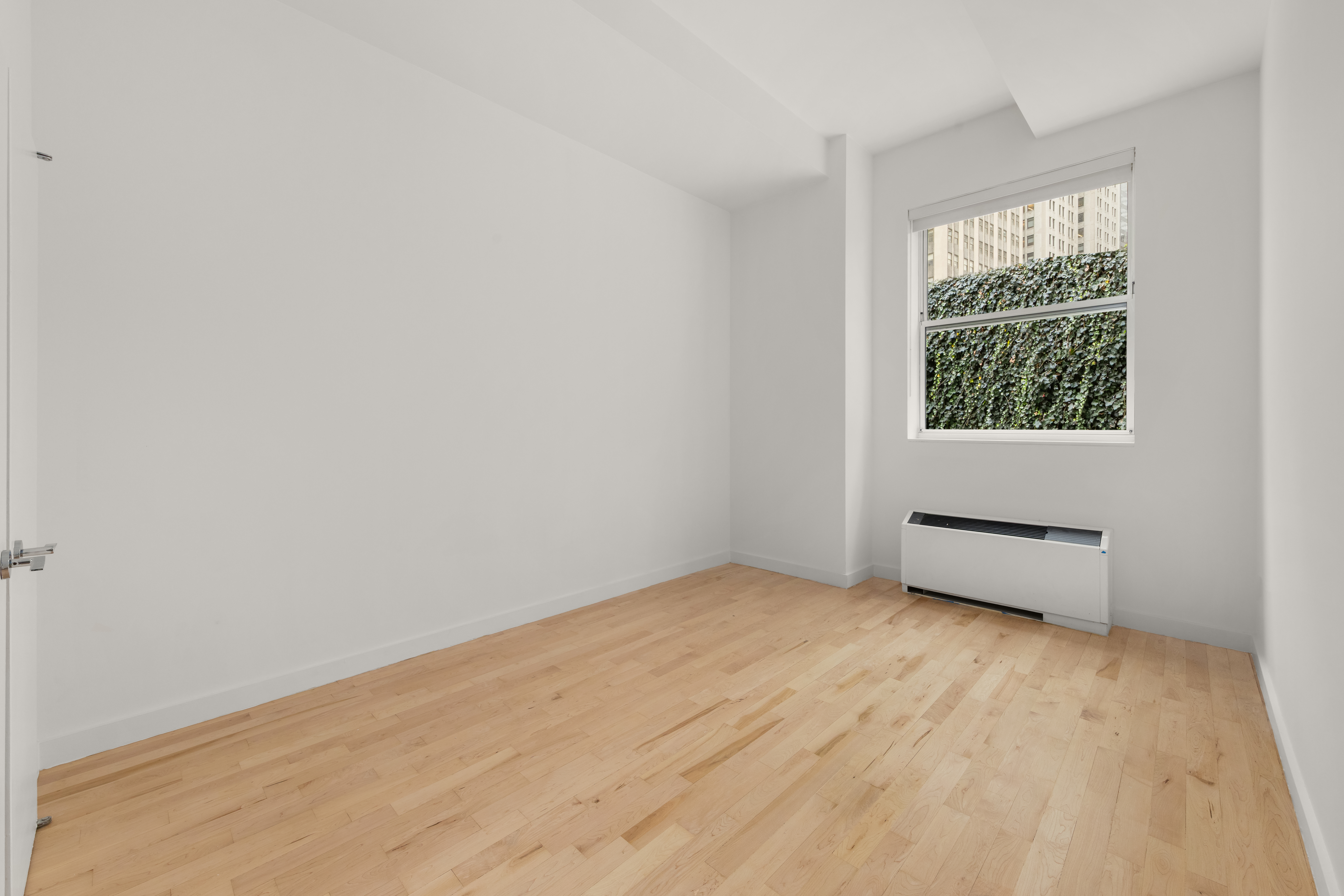 15 Broad Street, Unit 710 Manhattan, NY 10005 - Photo 6 of 11 an empty room with wooden floor and windows