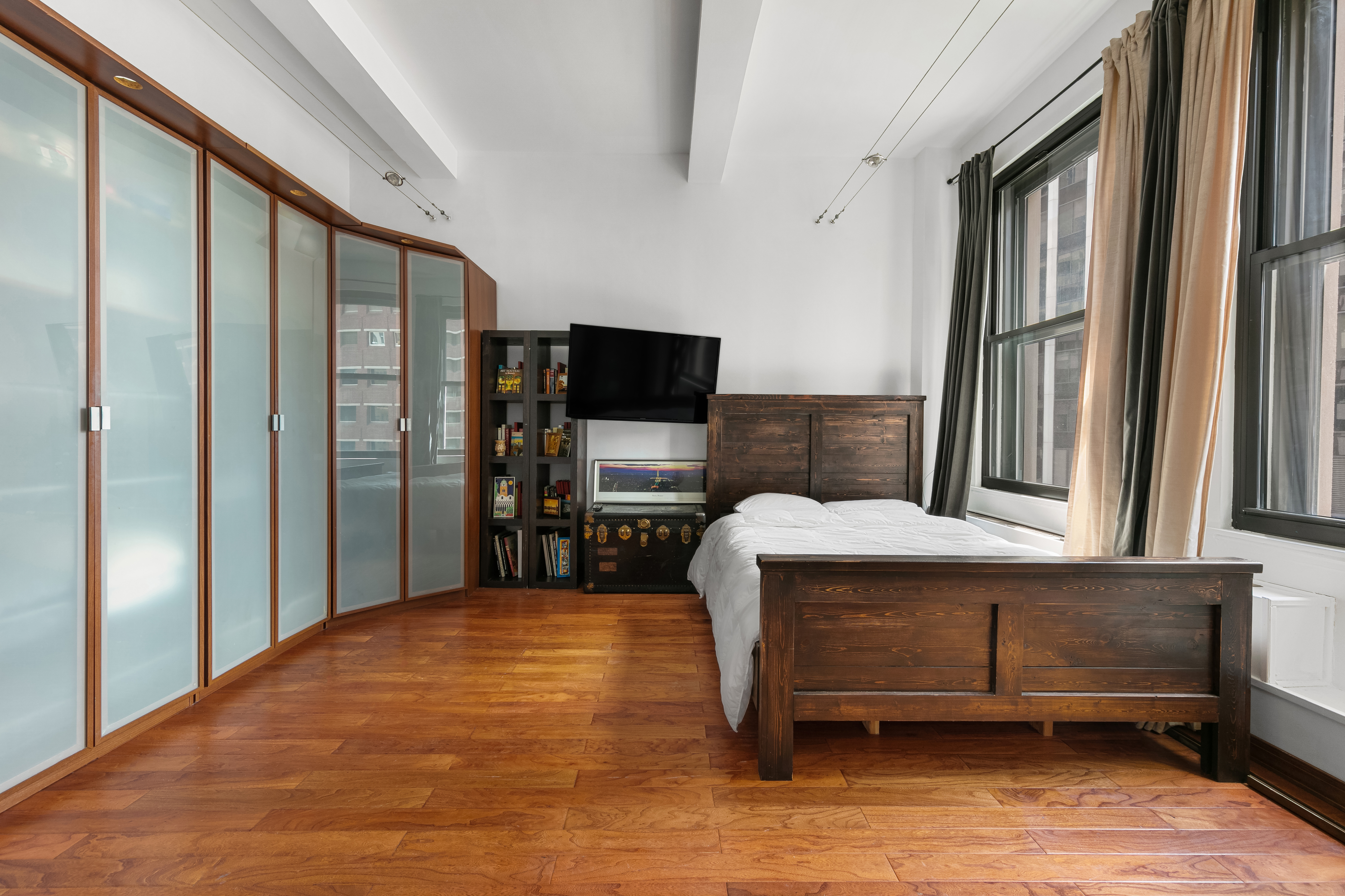 3 Hanover Square, Unit 10H Manhattan, NY 10004 - Photo 3 of 9 a bedroom with a bed and a flat screen tv