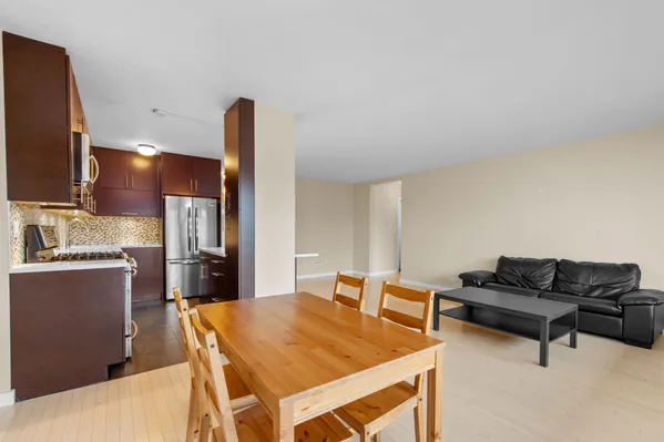 a living room with stainless steel appliances furniture a rug and a kitchen view