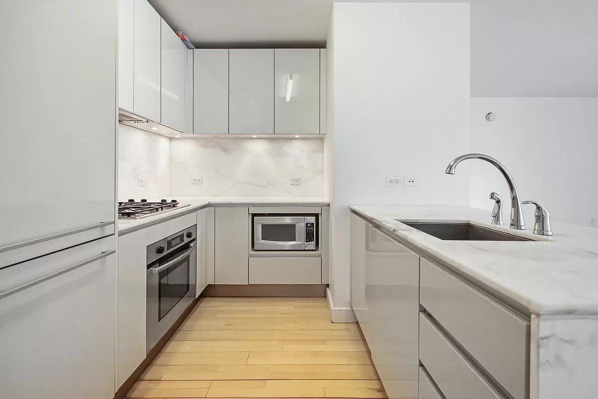 322 West 57th Street, Unit 38Q Manhattan, NY 10019 - Photo 3 of 16 a kitchen with a sink stove and cabinets