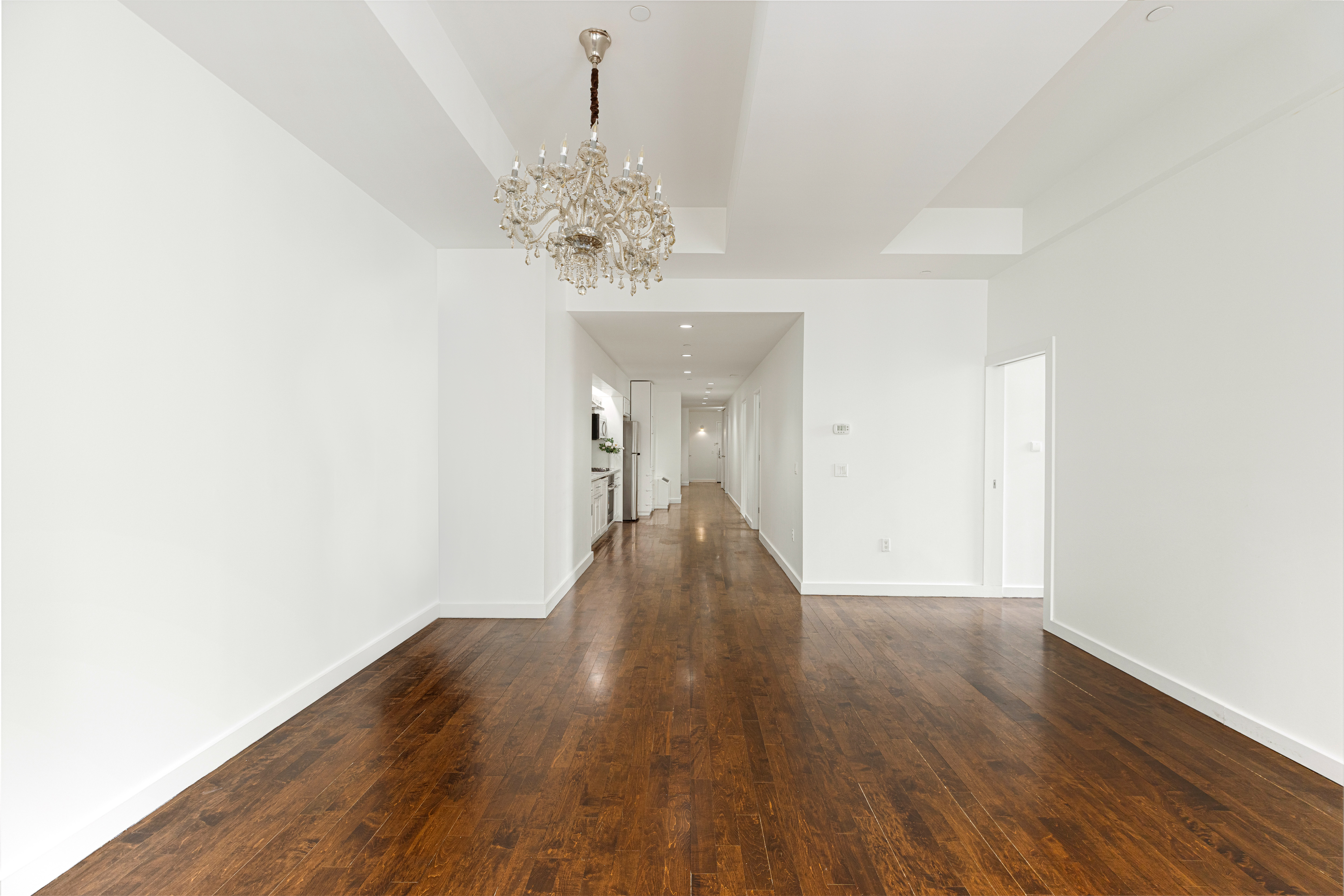 15 Broad Street, Unit 2300 Manhattan, NY 10005 - Photo 4 of 36 a view of a hallway with wooden floor and a chandelier