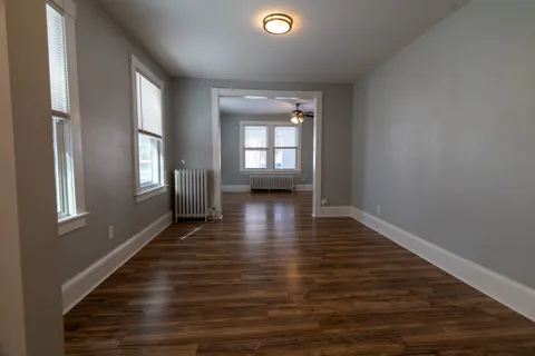 a view of empty room with wooden floor and fan