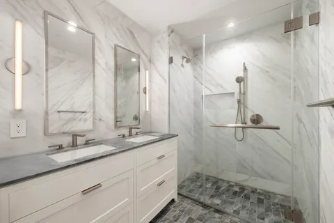 a bathroom with a double vanity sink mirror and shower