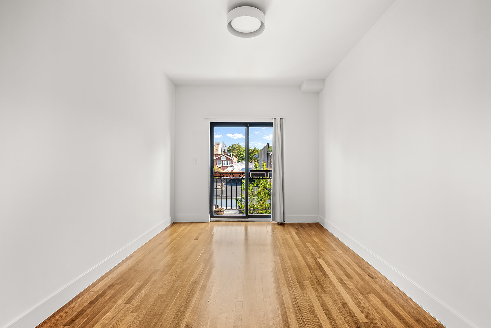 495 Rutland Road, Unit 3 Brooklyn, NY 11203 - Photo 8 of 12 a view of an empty room with wooden floor and a window
