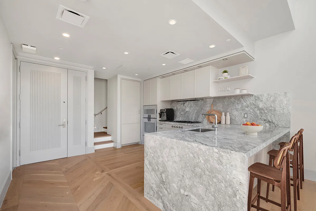 1059 3rd Avenue, Unit 10C Manhattan, NY 10065 - Photo 3 of 7 a kitchen with kitchen island a sink stainless steel appliances and cabinets