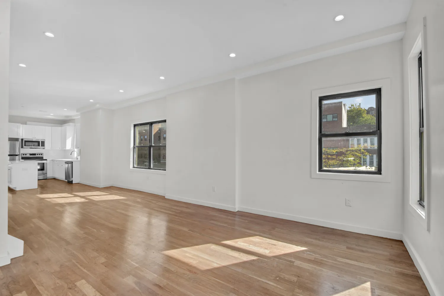 a view of an empty room with window and wooden floor