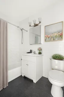 a bathroom with a granite countertop sink a toilet a mirror and shower