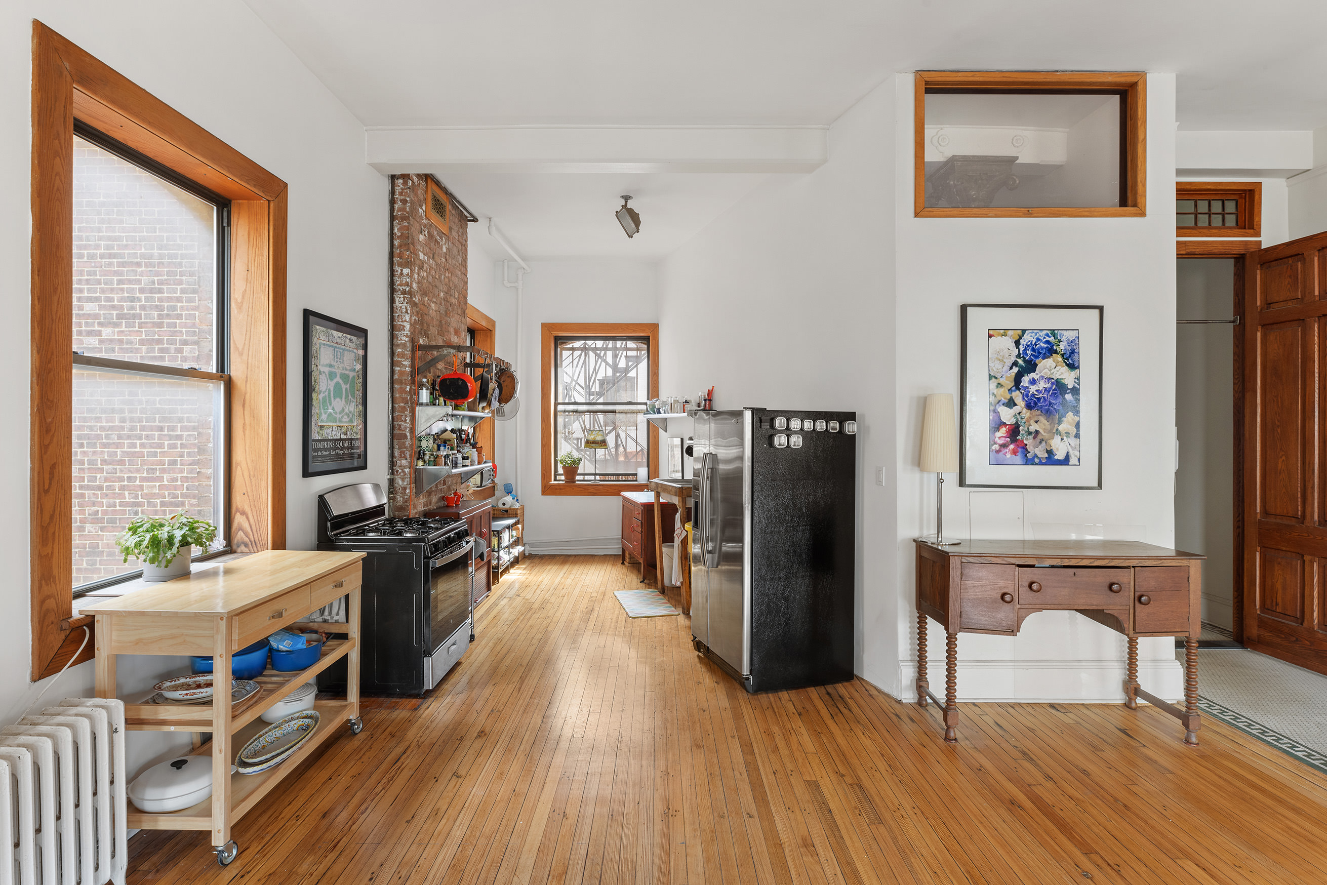 295 East 8th Street, Unit 3W Manhattan, NY 10009 - Photo 13 of 18 a living room with furniture a large window wooden floor and a table