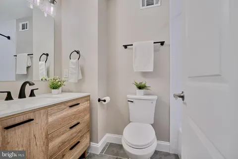 a bathroom with a granite countertop toilet sink and mirror