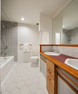 a spacious bathroom with a granite countertop sink a toilet mirror and bathtub