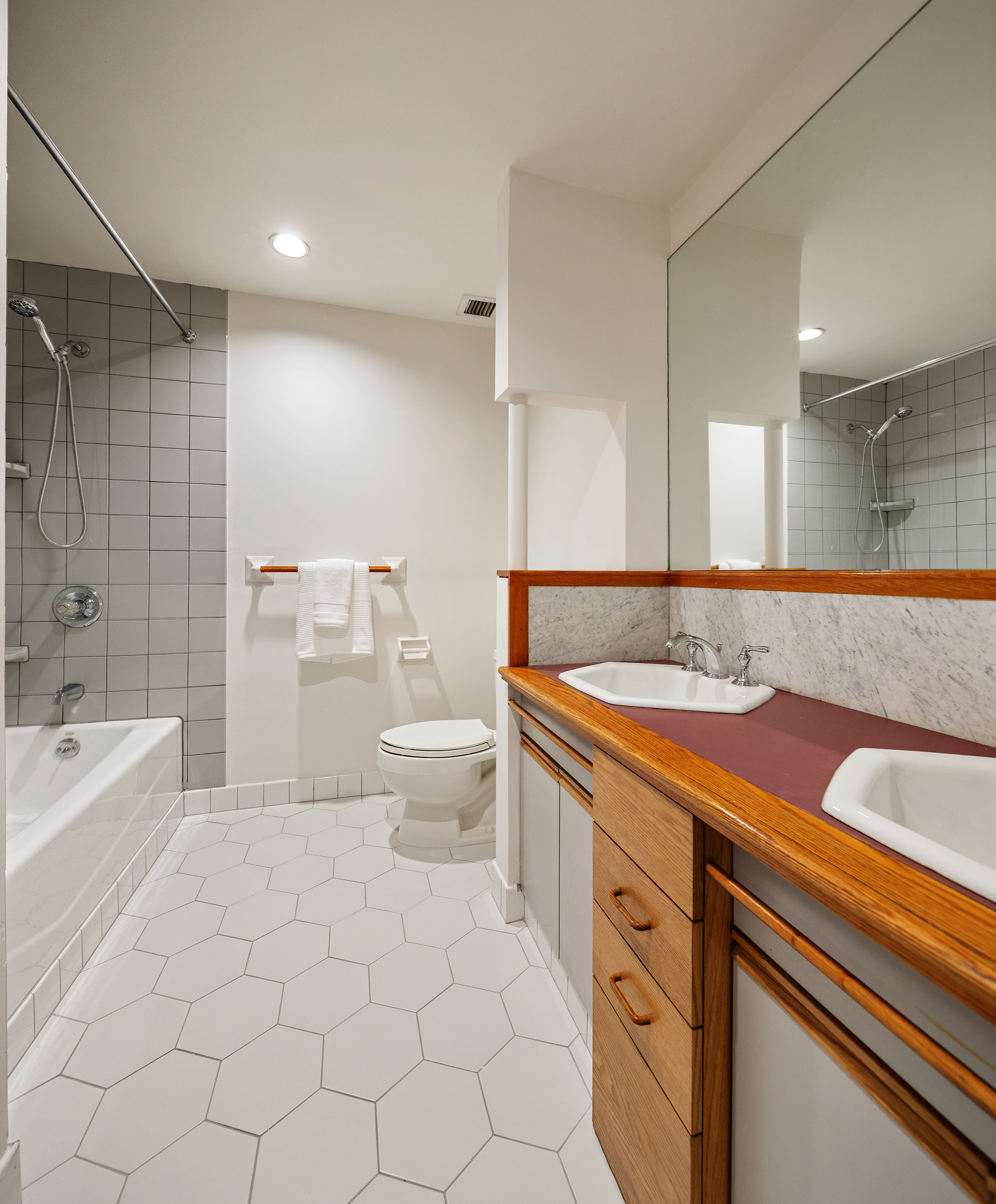 115 4th Avenue, Unit 2I Manhattan, NY 10003 - Photo 8 of 12 a spacious bathroom with a granite countertop sink a toilet mirror and bathtub