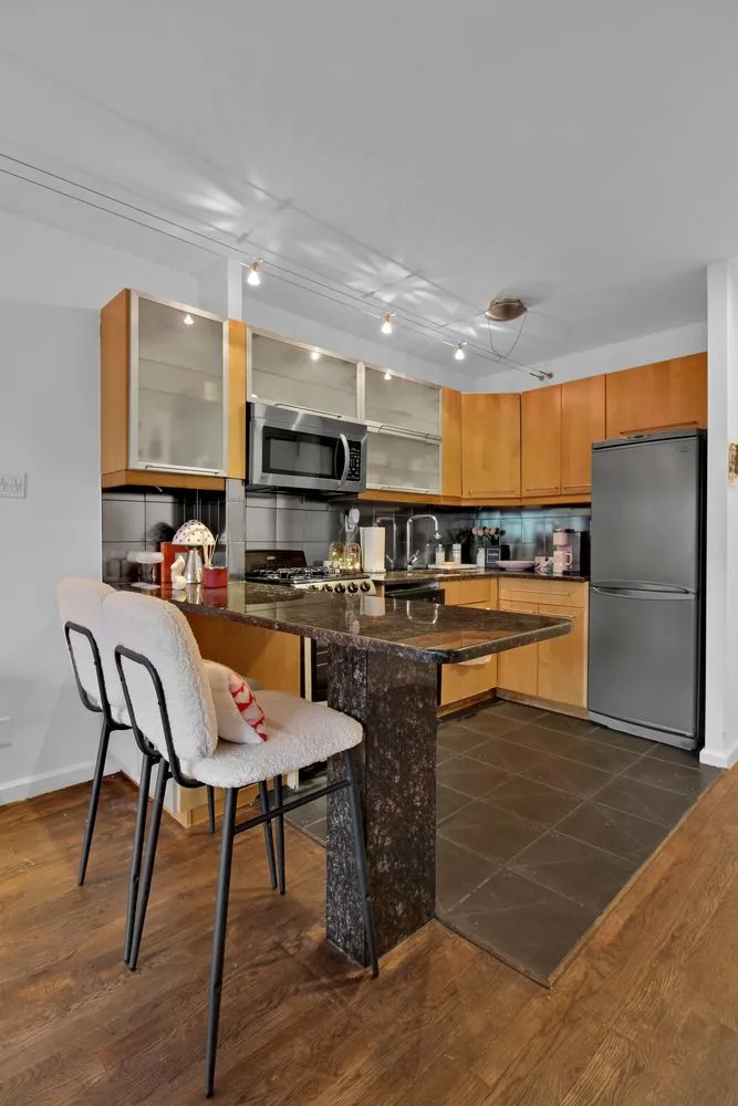 a open kitchen with stainless steel appliances granite countertop a stove a refrigerator a kitchen island and chairs with wooden floor