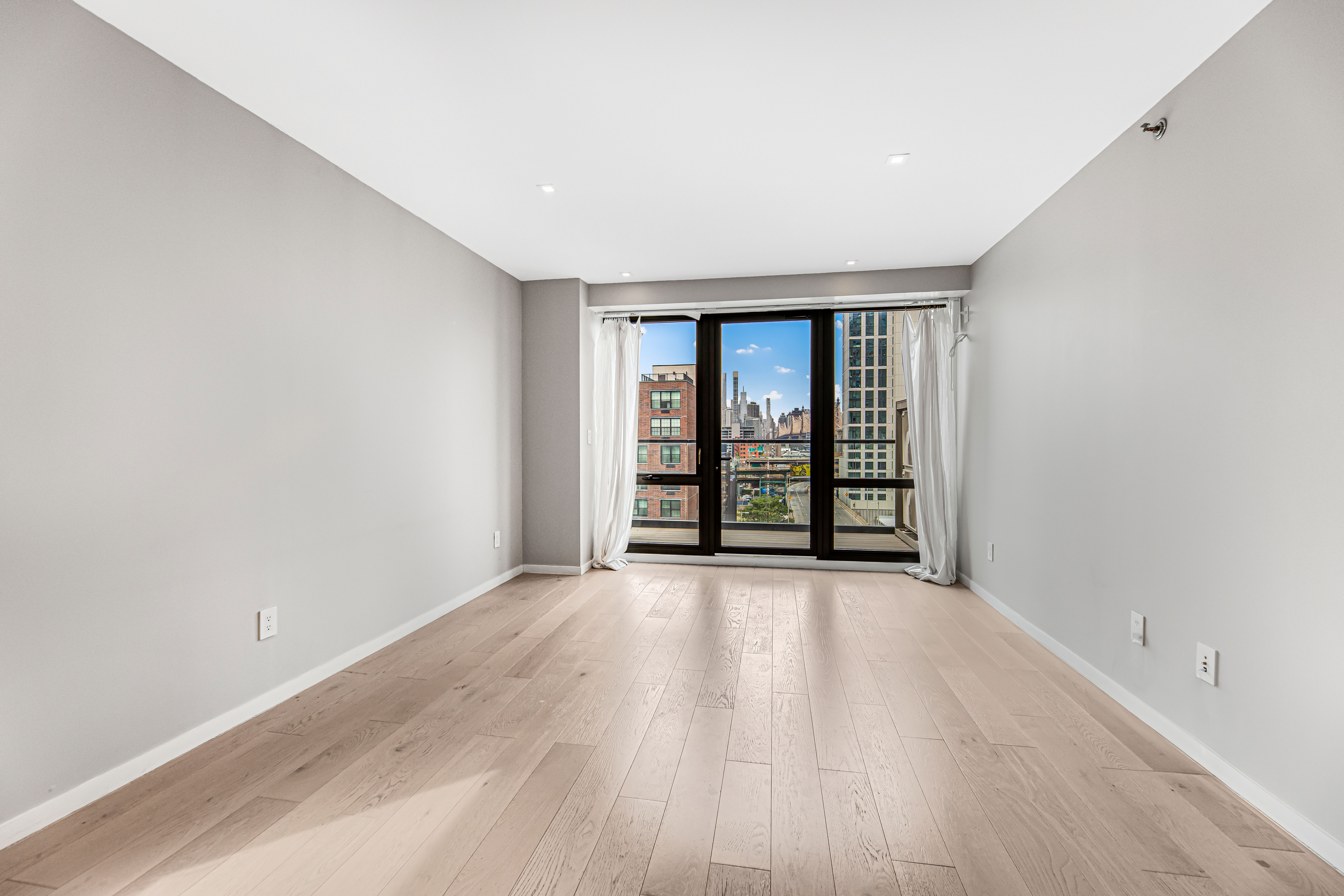 42-50 27th Street, Unit 9C Queens, NY 11101 - Photo 17 of 32 wooden floor in an empty room with a window