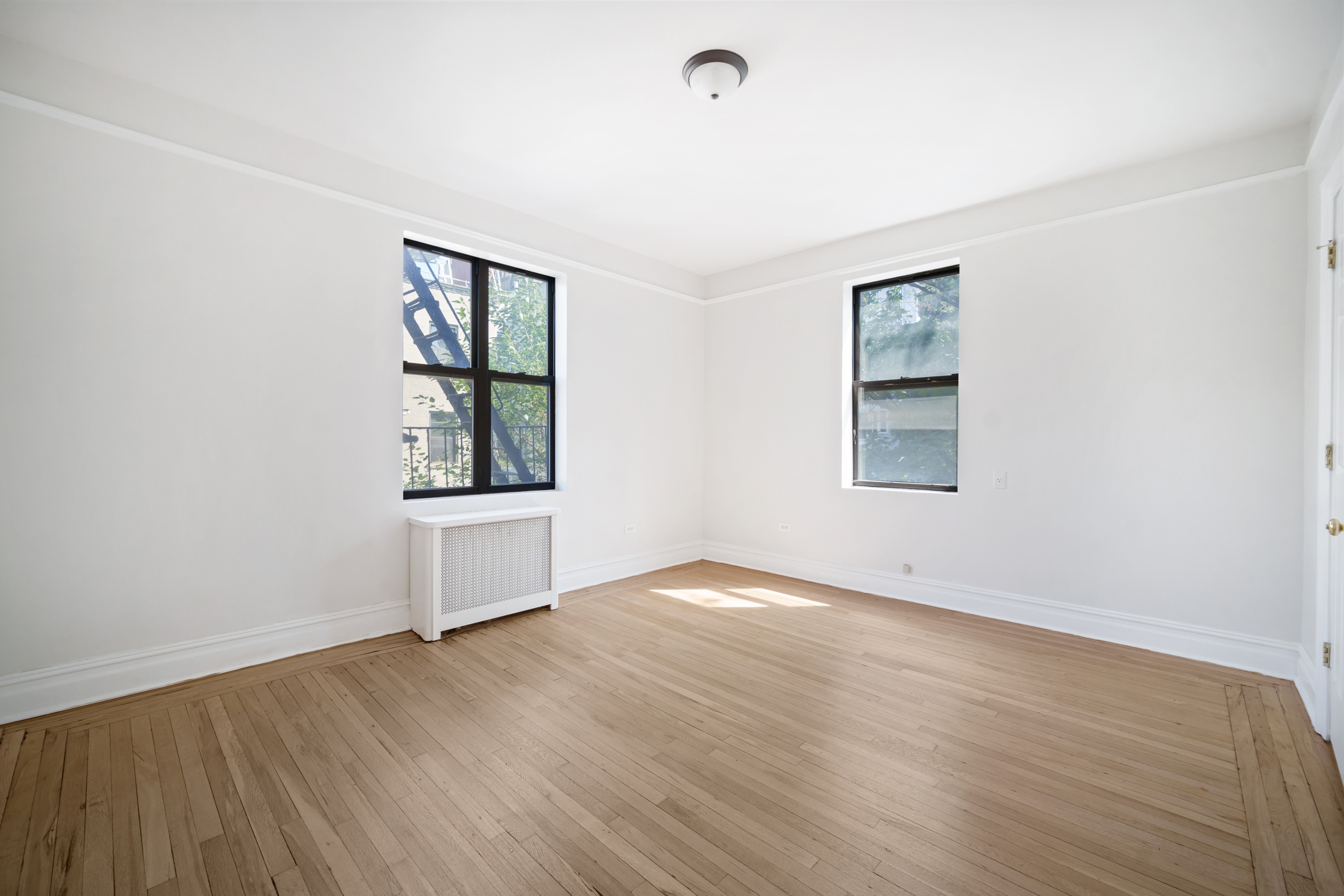 690 Riverside Drive, Unit 3F Manhattan, NY 10031 - Photo 6 of 19 an empty room with wooden floor and windows