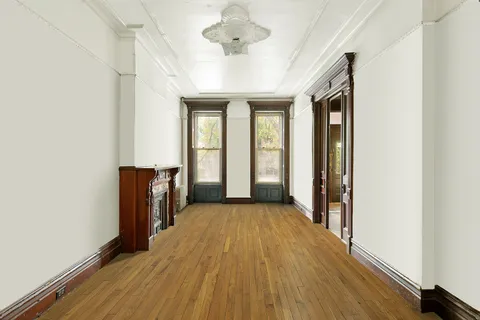 a view of a room with wooden floor a ceiling fan and windows